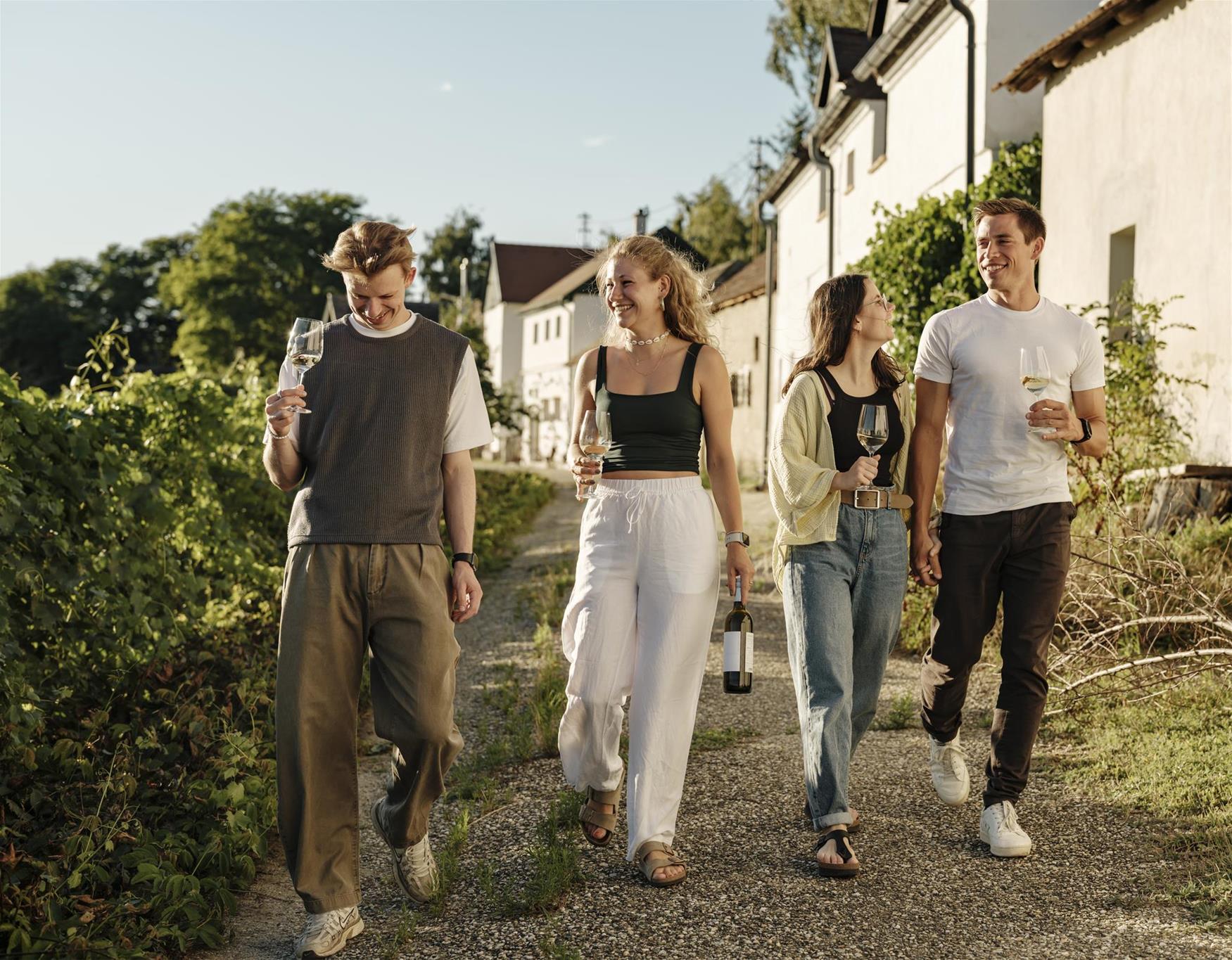4 junge Leute wandern mit einem Weinglas in der Hand